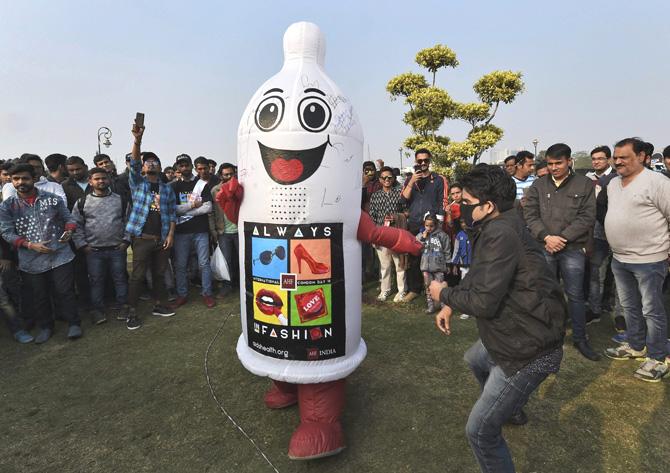 Passer-bys look on as an actor wearing a condom shaped costume performs during an event to mark International Condom Day at Connaught Place in New Delhi on Tuesday. Pic/PTI
