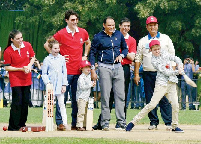 Canadian PM Justin Trudeau, with son Hadrien, daughter Ella-Grace, and former Indian cricket captain Mohammad Azharuddin, watches as his son Xavier bats, during a visit to a school, in New Delhi. Pic/PTI