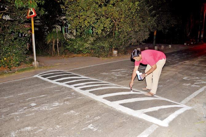 Social worker Sameer Vartak paints the first of the eight speed breakers on Wednesday night. Pics/Hanif Patel