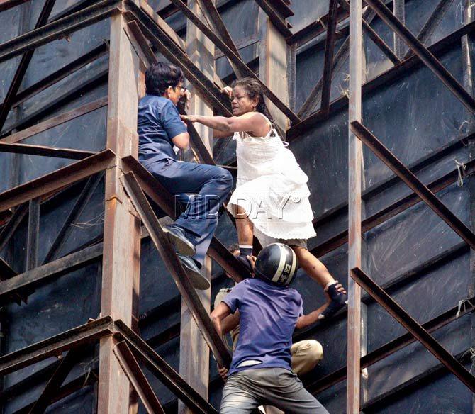 Sapna Pereira claws her way up behind a hoarding at Girgaum Chowpatty as rescuers give chase. Pics/Bipin Kokate