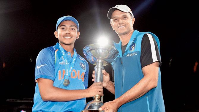 Prithvi Shaw holds the U-19 World Cup trophy with coach Rahul Dravid in Mount Maunganui on Saturday. PIC/ICC