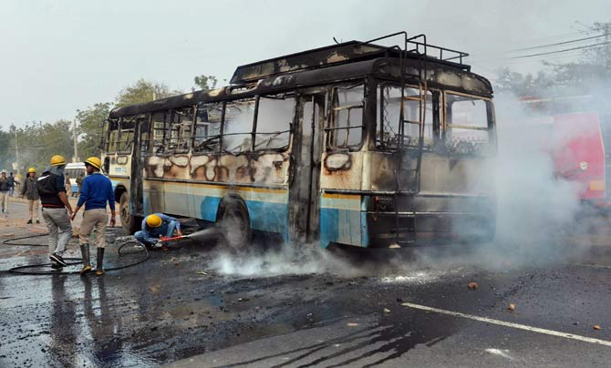 Firefighters try to douse a fire after alleged activists of the Karni Sena torched a Haryana roadways bus at NH-248 during a demonstration against the release of 