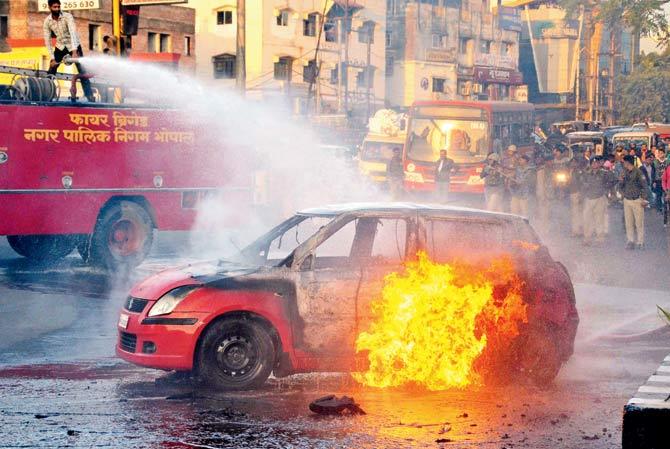 A firefighter tries to douse flames after Karni Sena activists torched a car during a demonstration against the release of the controversial film Padmaavat in Bhopal yesterday. Pic/PTI