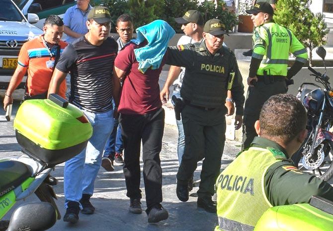 Police officers escort a bomb attack suspect in Barranquilla, Colombia, on January 27, 2018. At least three police officers were killed and fourteen other were wounded when alleged drug traffickers detonated a remote controlled bomb at a station in the northern city of Barranquilla. Pic/AFP
