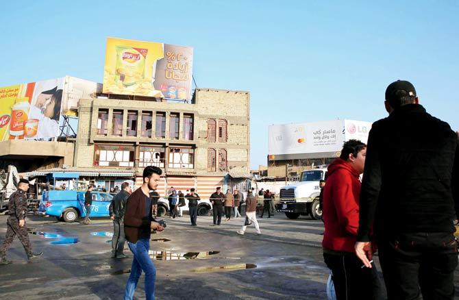 Iraqis walk past the area where the bombing took place. Pic/AFP