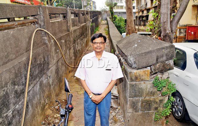 Ketan Gandhi from Sarla Sadan near the triangular-topped stone pillar of French Bridge he would sit on during childhood games of gully cricket. Labourers have not succeeded in dislodging this last precariously perched piece of the bridge wall. Pic/Atul Kamble 