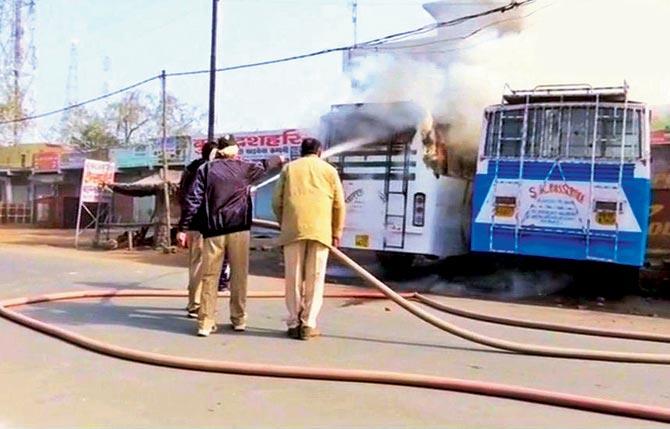 Firemen try to douse flames after two buses and some shops
