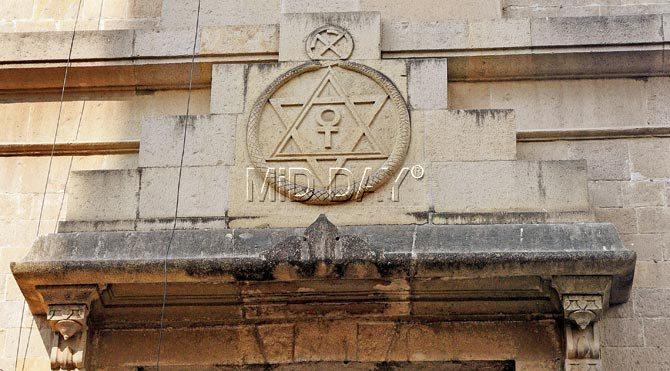 Close-up of the Theosophical Society seal which blends eclectic elements: the Greek allusion to infinity with the Ouroboros symbol of a serpent biting its tail, the universal Hexagram star, the Crux Ansata from Egypt suggesting resurrection, the Swastika and Om emblems