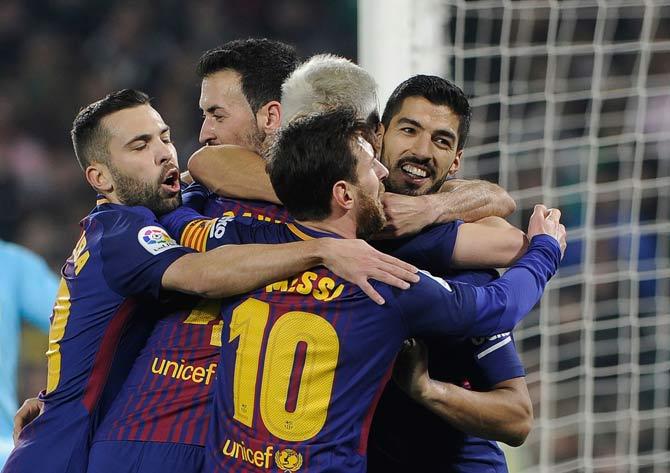 Barcelona forward Luis Suarez celebrates with teammates after scoring a goal against Real Betis. Pic/ AFP