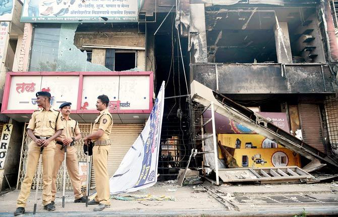 Policemen stand guard near vandalised shops following the violence during celebrations of 200th anniversary of the Battle of Bhima Koregaon, near Pune. Pic/ PTI