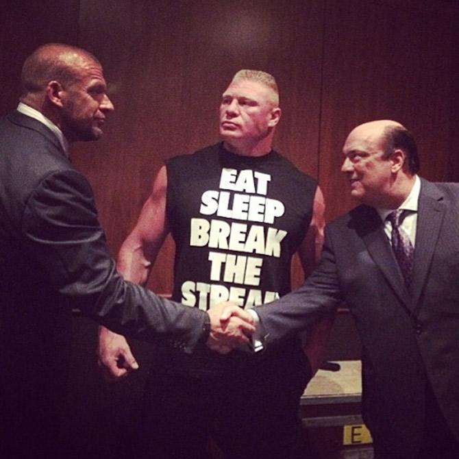 Brock Lesnar giving the cold stare to his boss Triple H while he shakes hand with Brock's manager Paul Heyman. Brock Lesnar and Triple faced each other at WrestleMania 29. Triple H won the match