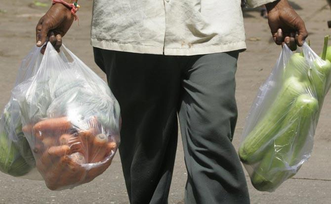 A local resident carries home plastic bags full of vegetables in Mumbai