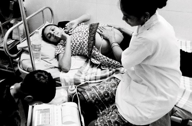 Khambe takes a picture of his wife lying on the bed of a hospital for transcervical amnioinfusion