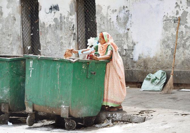 A woman looks for useable items from a garbage bin in New Delhi. Pic/AFP