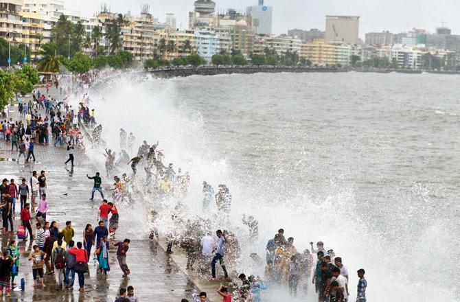 People enjoy the high tide as rains lash city, at Marine Drive on Sunday