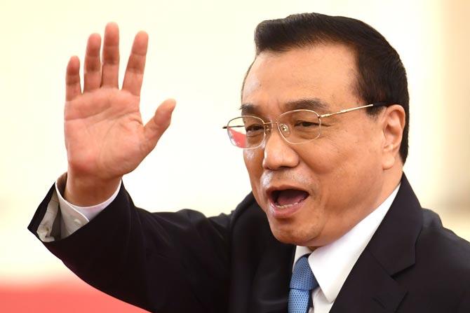 Chinas Premier Li Keqiang waves to reporters as he leaves a press conference after the closing session of the National People