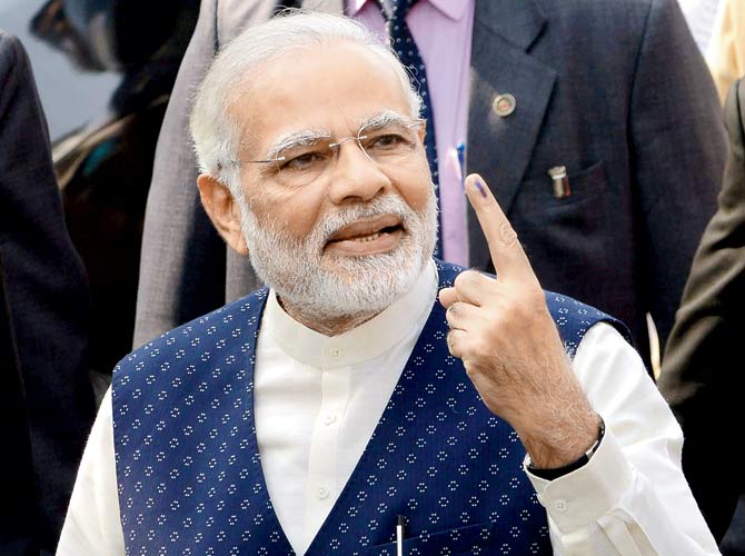 Prime Minister Narendra Modi poses for the media with an inked finger