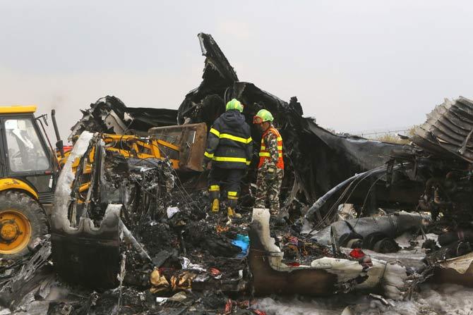Nepalese rescuers stand on the debris after a passenger plane from Bangladesh crashed at the airport in Kathmandu, Nepal. Pic/AFP