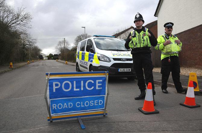 British police officers stand on duty as members of the Army work in a residential street in Alderholt, southern England, on March 15, 2018, as investigations and operations continue in connection with the major incident sparked after a man and a woman were apparently poisoned in a nerve agent attack in Salisbury on March 4. Britain expelled 23 Russian diplomats over the nerve agent poisoning of a former spy, and suspended high-level contacts, including for the World Cup, as the US joined it in blasting Moscow at the UN on March 14. British Prime Minister Theresa May told Britain