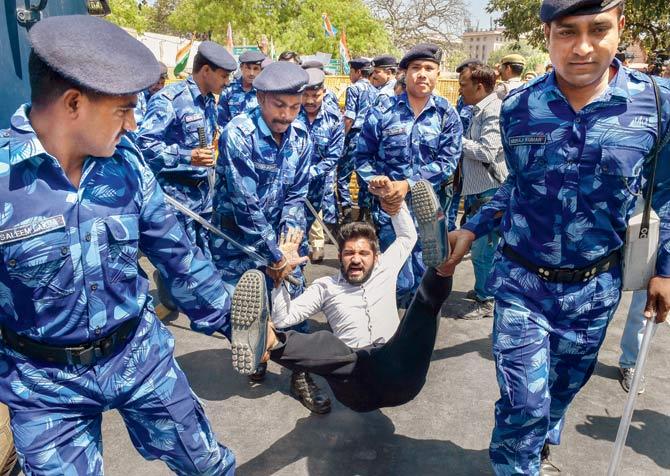 RAF personnel take away an NSUI activist, as he raises slogans against Union HRD Minister Prakash Javadekar in New Delhi, on Friday. Pic/PTI
