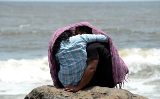 A young couple sits together on a rocky outcrop off the Arabian Sea in Mumbai on July 3, 2015    