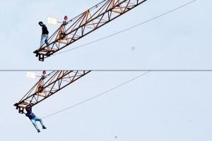 Distressed, labourer jumps off crane, then hangs on for his dear life!