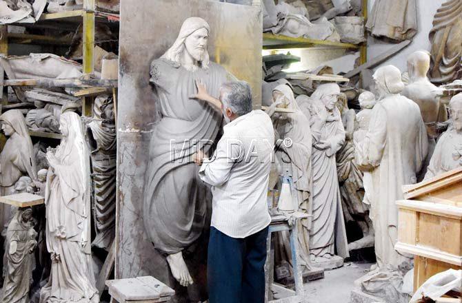 A senior worker touches up a mould of Jesus Christ