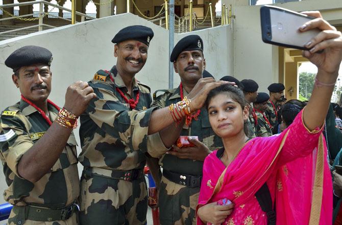 A girl clicks selfie with Border Security Force (BSF) jawans after tying 'rakhi' to them on the occasion of Raksha Bandhan festival at Attari-Wagah border