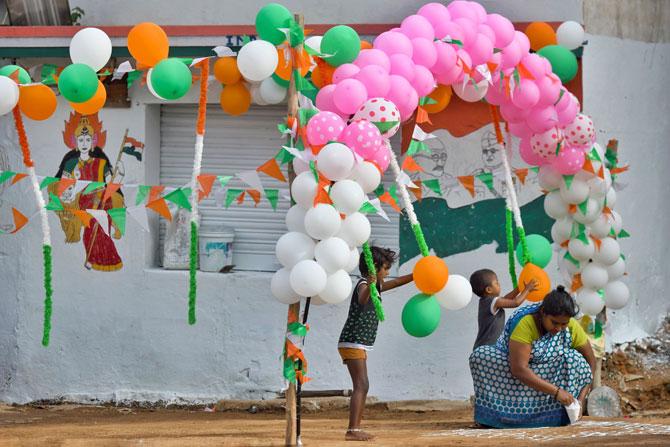 A woman decorates a sidewalk to celebrate India's 73rd Independence Day in Bangalore 