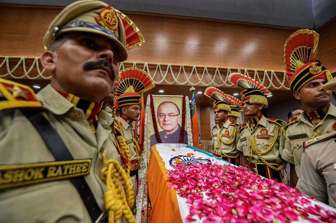 Police personnel stands beside the mortal remains of former Finance Minister and BJP leader Arun Jaitley before his remains were taken for the last rites to Nigam Bodh Ghat from BJP headquarters in New Delhi