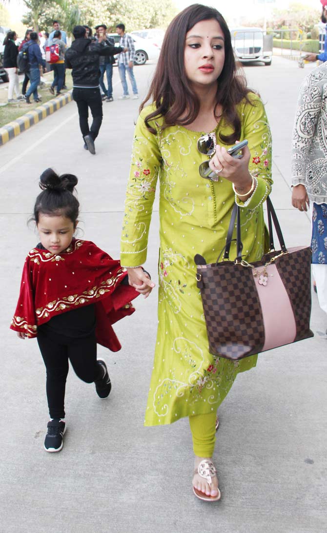 Sakshi Dhoni had her hands full with a bag and phone in one hand and Ziva Dhoni in the other hand.