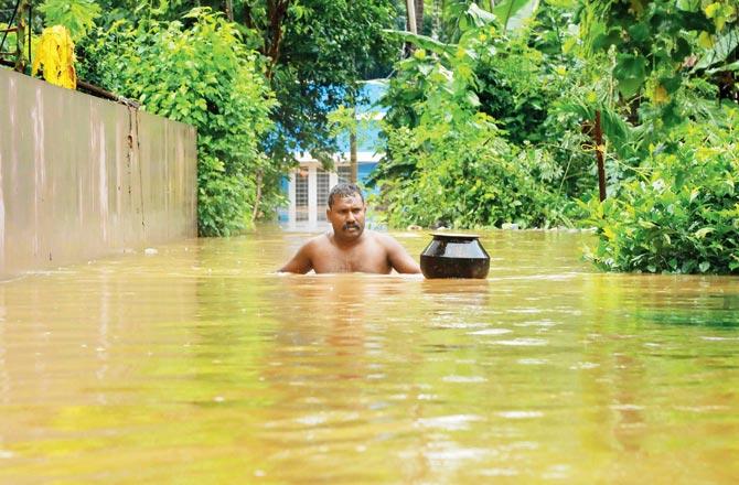 A man makes his way through a flooded road in Eloor, Ernakulam district of Kerala on Friday. Pics/AFP
