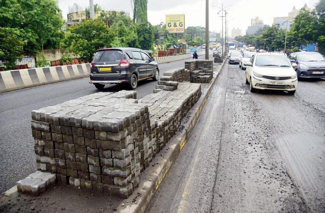 The potholes on the overbridge at Waghbil being filled with paver blocks