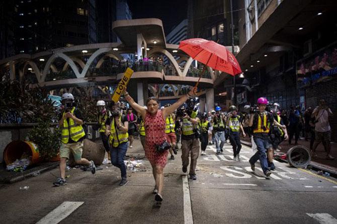 A woman holds up an umbrella and license plates, one that reads 'love', during violent protests between riot police and demonstrators in the Causeway Bay district of Hong Kong on October 1, 2019. Police fanned out across Hong Kong on October 1 in a bid to deter pro-democracy protests as the city marked communist China's 70th birthday, with local officials attending a closed-door flag-raising ceremony behind the closed door.