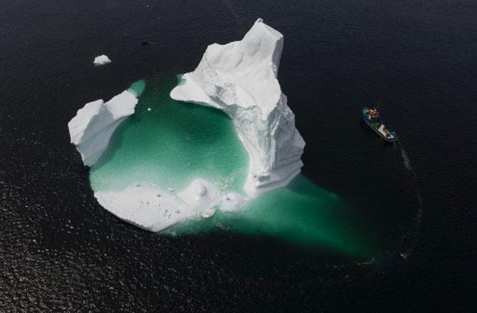 This aerial photo shows the boat of Captain Edward Kean passing an iceberg in Bonavista Bay on June 29, 2019, in Newfoundland, Canada. The abundance of icebergs, which continue to venture further into Canadian waters, has created a new form of tourism, iceberg sightseeing. In 2018, more than 500,000 tourists visited the province of Newfoundland, contributing nearly 570 million Canadian dollars (389 million euros) to the local economy, according to the estimates of the provincial government.