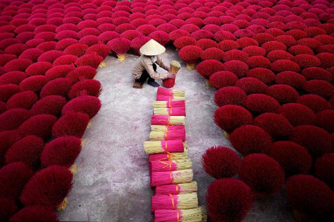 This picture taken on January 3, 2019, shows a Vietnamese woman collecting incense sticks in a courtyard in the village of Quang Phu Cau on the outskirts of Hanoi. In Vietnam's 'incense village', hundreds of workers are hard at work dying, drying and whittling down bamboo bark to make the fragrant sticks ahead of the busy lunar new year holiday.