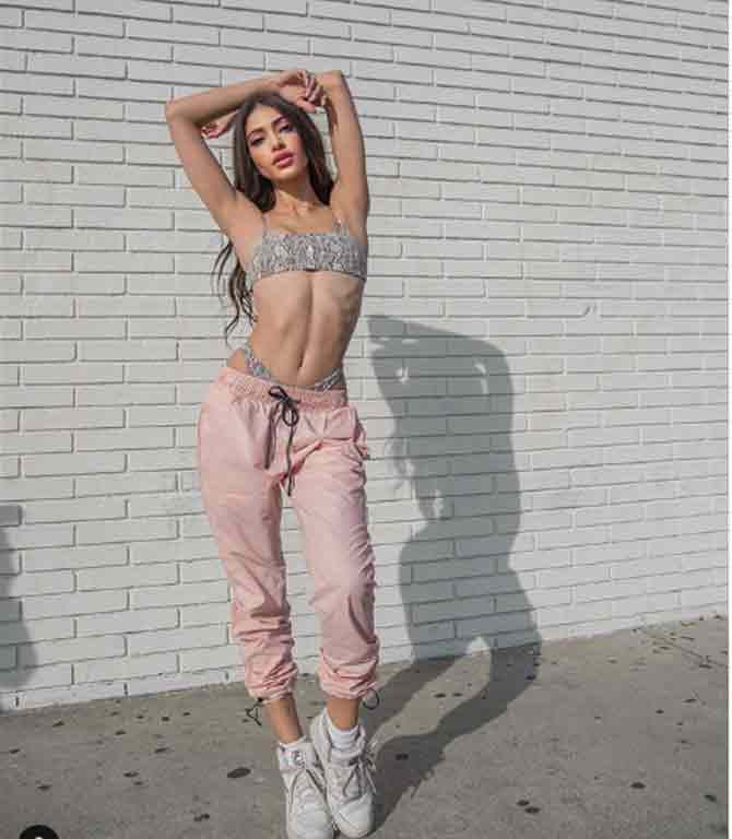 In this photo, she shows off her well-toned midriff in a grey printed bralette and blush pink joggers with white sneakers.