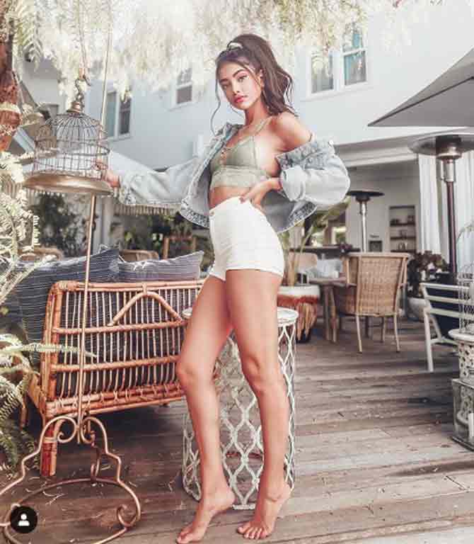 She flaunts her toned legs in this outfit including her white shorts and jacket with her hair tied into a messy high pony, shot on the terrace of a hotel in California.