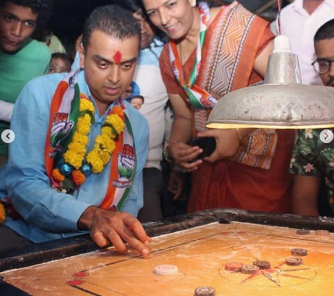 In photo: Congress leader Milind Deora takes some time off his political rally and enjoys a game of carrom with the locals in his constituency