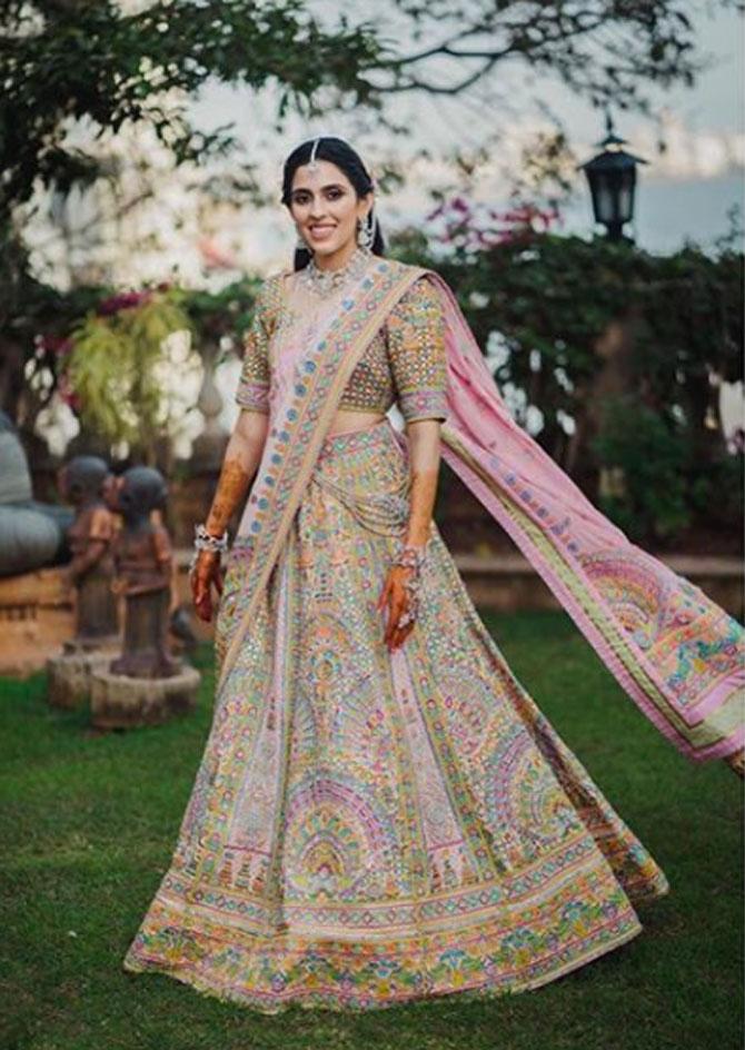 Shloka Mehta exudes romance in a pastel-hued hand-embroidered and heavily embellished lehenga with a matching blouse. She accentuated her look with 'hathful' and a 'maangtika'.