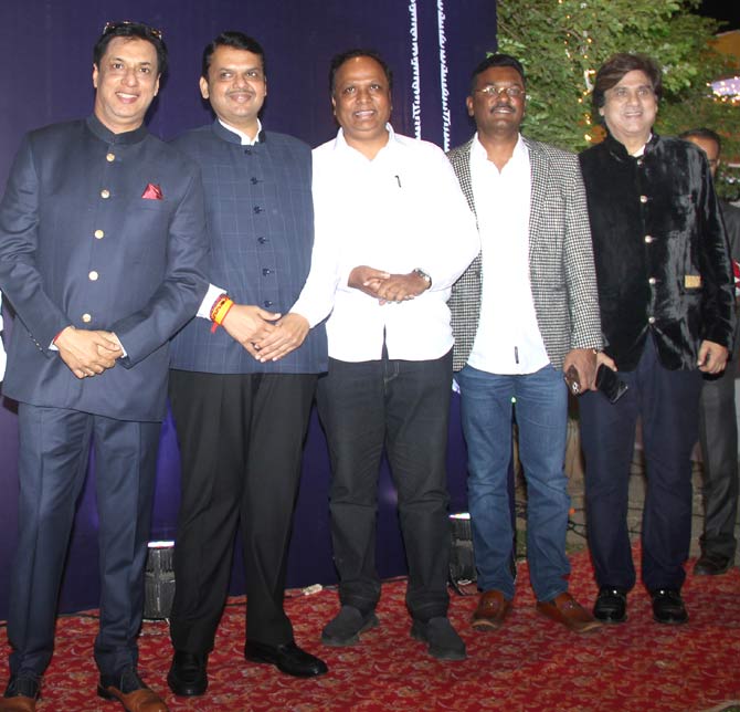The reception also saw the presence of political leaders. Seen here are former chief minister Devendra Fadnavis and BJP leader Ashish Shelar posing for photographers along with other dignitaries. Filmmaker Madhur Bhandarkar completes the group photograph.