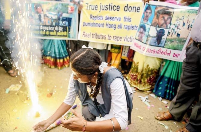 A schoolgirl lights firecrackers after the accused were killed. Pic/PTI