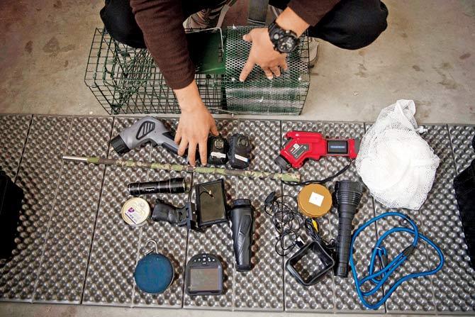 Sun Jinrong and his assistant (left) Prepare a trap as they search for a missing cat in a residential compound in Beijing;  the high-tech gadgets used by Jinrong. Pics/AFP
