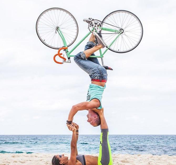 In the pic: Honza and Claudine are performing a dangerous Acroyoga position where Claudine is lifting her husband in the air along with a bicycle.