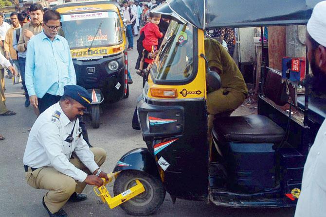 A cop locks the wheel of an auto after the driver refuses fare at Kurla West.