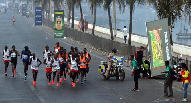 A passer-by lends a helping hand to a man who had apparently fallen off his bike while the runners nonchalantly continue with the race at the Tata Mumbai Marathon. Pic credit/Sameer Abedi