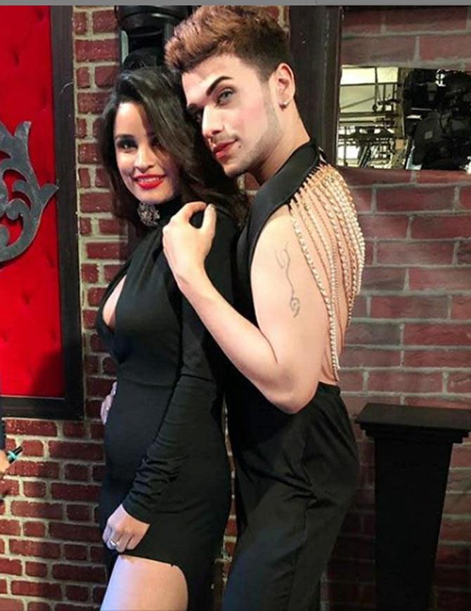 Faizy striking a pose at the finale episode of Ace of Space in his elegant backless black jumpsuit combined with golden detailing and vibrant makeup.