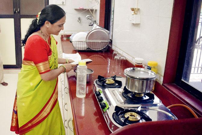 His wife, Pooja, carries out the ritual boiling of milk to signal their move to the new home