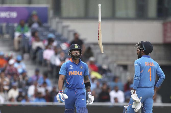 India's captain Virat Kohli, left, throws his bat in frustration after being dismissed by New Zealand's Trent Boult during the Cricket World Cup semi-final match between India and New Zealand at Old Trafford in Manchester, England