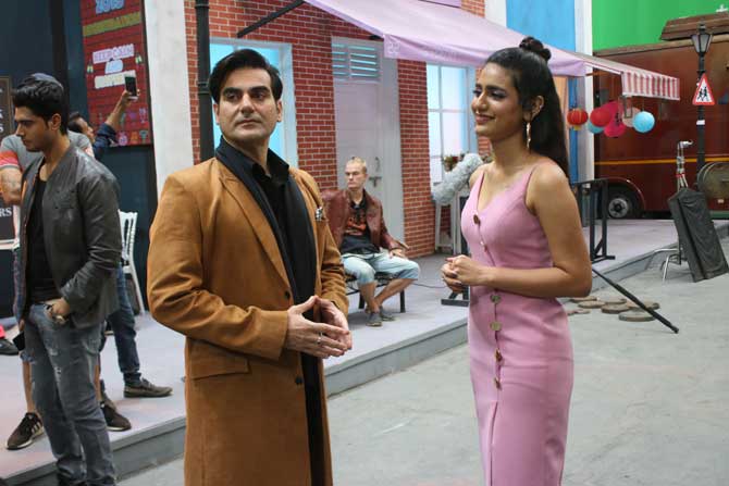 For the shoot, Priya opted for a pink thigh-slit spaghetti dress, which she paired it with beige stilettos and hoops. Her co-star donned a classy black shirt and pants, along with a brown jacket and black shoes.